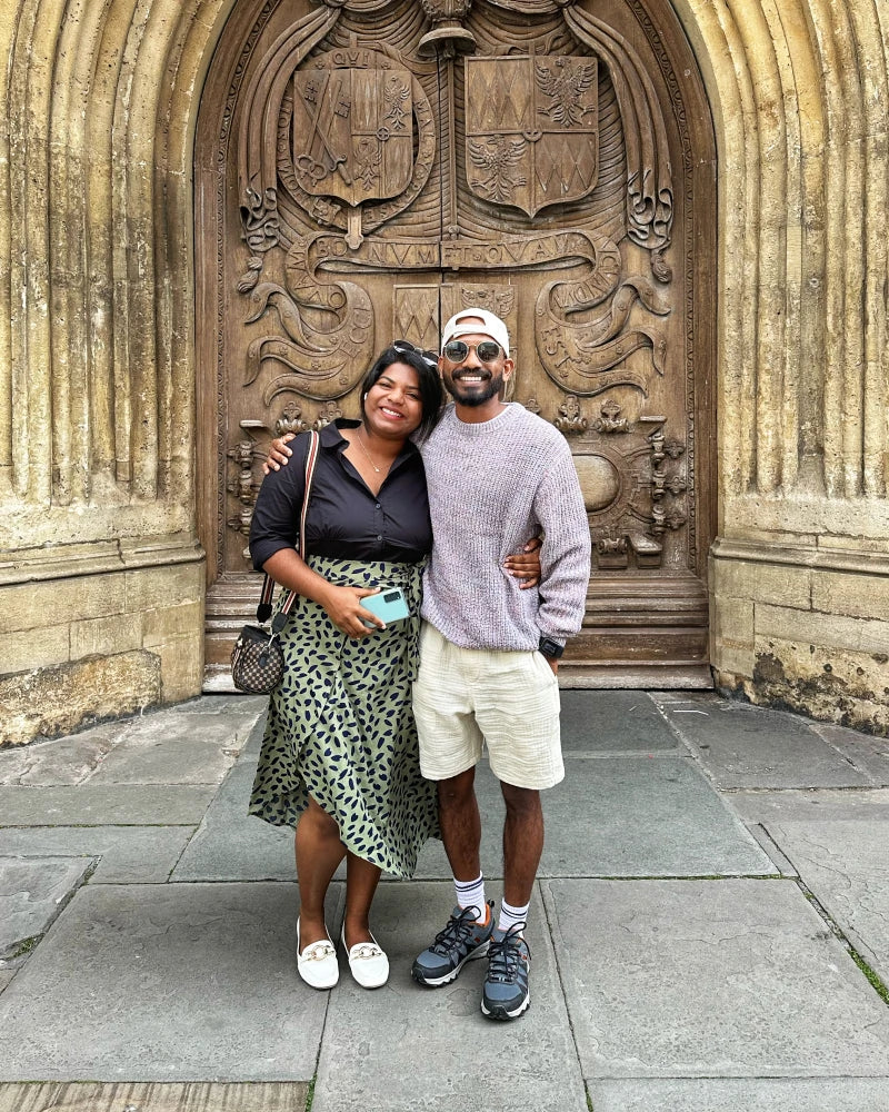 Two people standing in front of a large ornate wooden door.