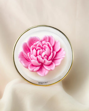 Pink flower on a round white plate with a gold rim against a beige background