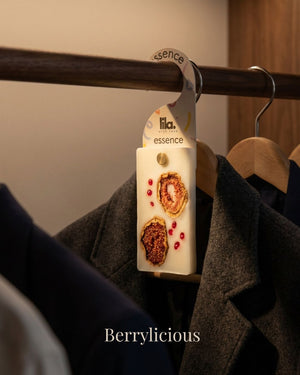wax sachet from lila with love infused with dried fig and pepper cones hanging on a wooden hanger on wooden wardrobe with cloths around them