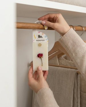 Person holding a wax sachet from  Lila with love  with a dried flower on a hanger.