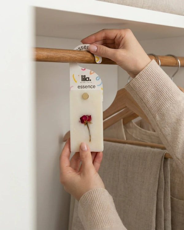 Person holding a wax sachet from  Lila with love  with a dried flower on a hanger.