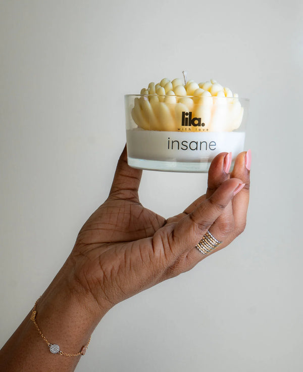 Insane soy wax candle with yellow petal design in clear glass jar, held by hand, from Lila with Love