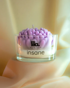 Insane soy wax candle with purple petal design in clear glass jar, held by hand, from Lila with Love