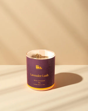 Lila Lavender Lush candle in a purple container on a beige background