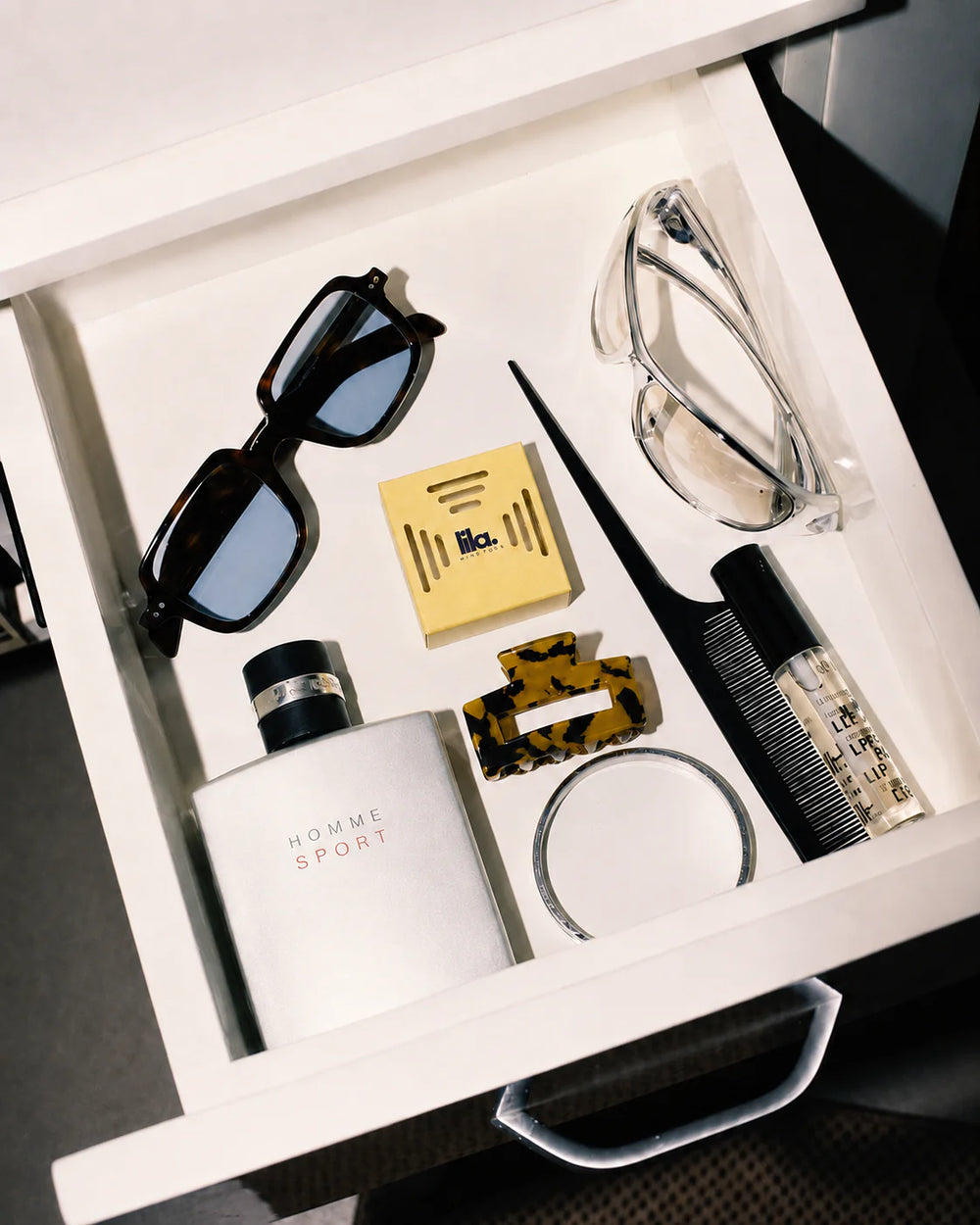 A yellow lila with love scented wax pod in an organised vanity drawer with sunglasses, a fragrance bottle, comb and hair claw