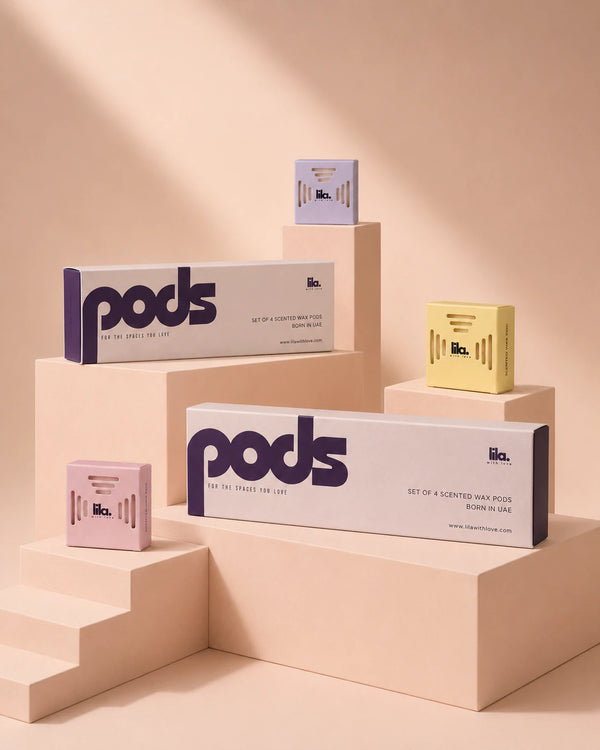 lila with love pods packaging on blush plinths — two "set of 4 scented wax pods" boxes with individual lilac, yellow and pink pods