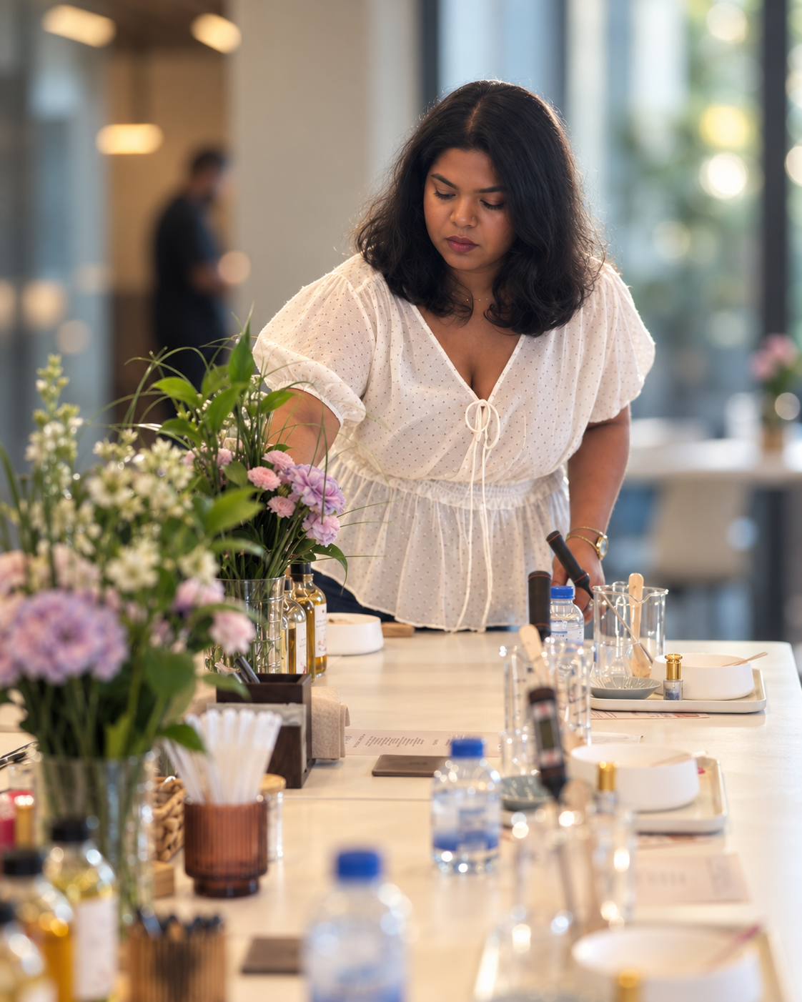 The Lila host sets a long workshop table with fresh flowers, fragrance oils and pouring tools