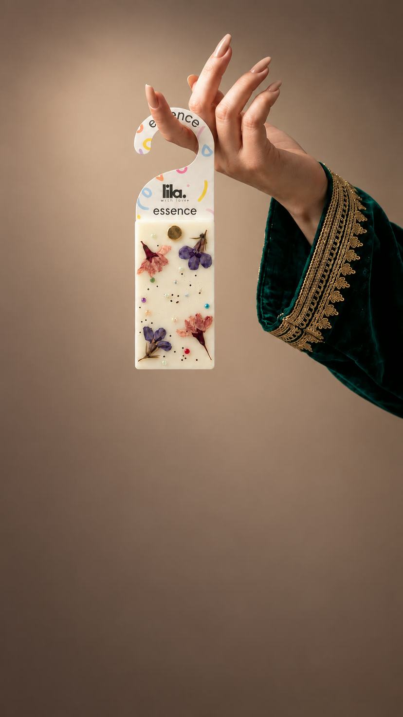 A hand lifts a Lila wax sachet pressed with dried flowers
