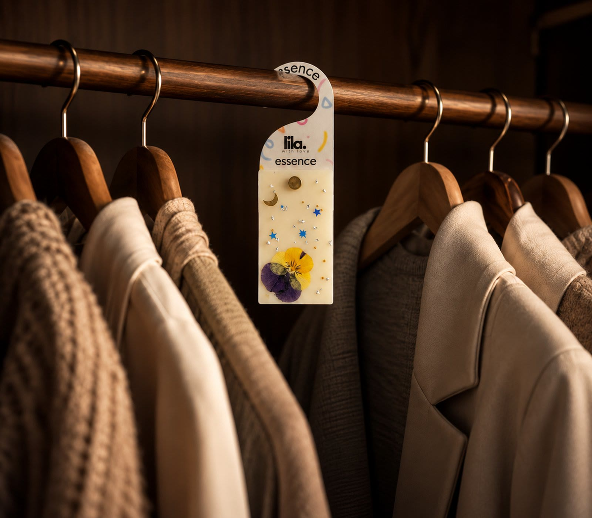 A Lila wax sachet with a pressed pansy hanging on a walnut wardrobe rail