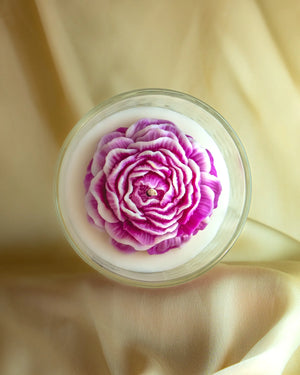 pink layered flower soy wax candle in clear glass jar by Lila with Love, top view on satin background