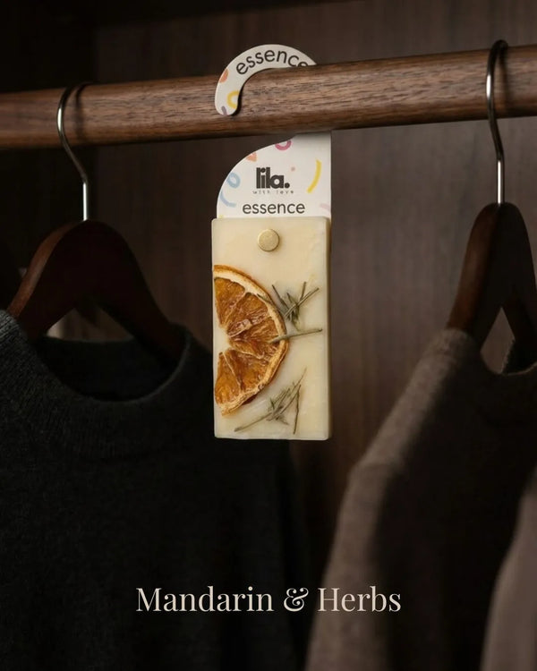 wax sachet from lila with love infused with dried lemon slice and rosemary  hanging on a wooden hanger on wooden wardrobe with cloths around them