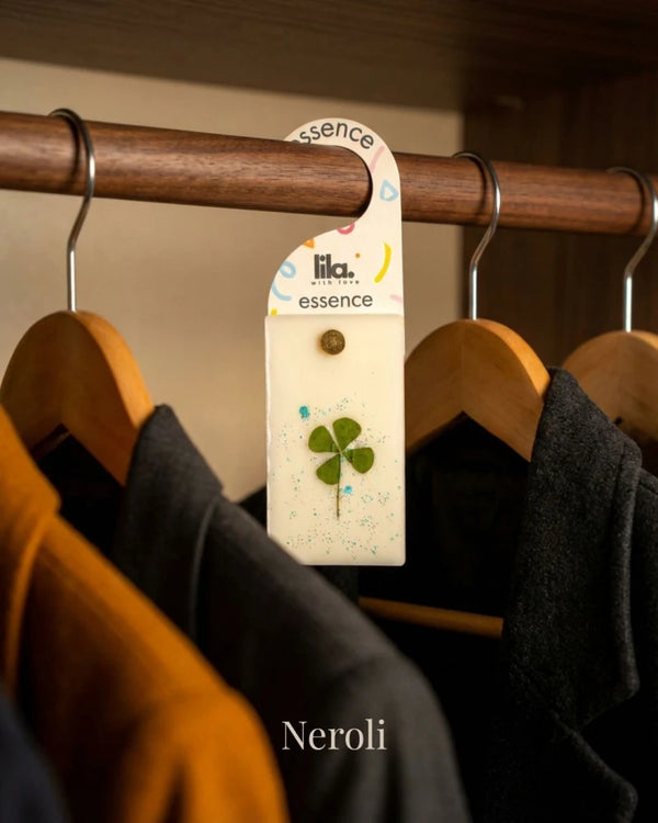 wax sachet from lila with love infused with dried  flower hanging on a wooden hanger on wooden wardrobe with cloths around them