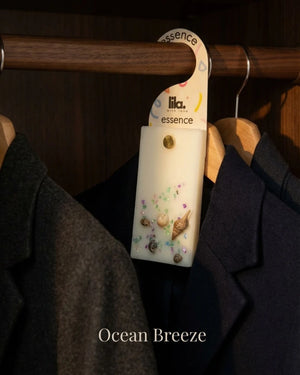 wax sachet from lila with love infused with sea shells hanging on a wooden hanger on wooden wardrobe with cloths around them