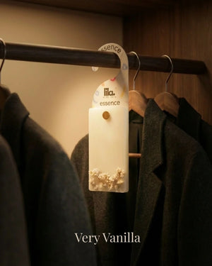 wax sachet from lila with love with white babys breath  buds  hanging on a wooden hanger on wooden wardrobe with cloths around them