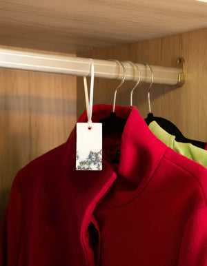 Red coat with a wax sachet featuring dried lavender, hanging on a rack.